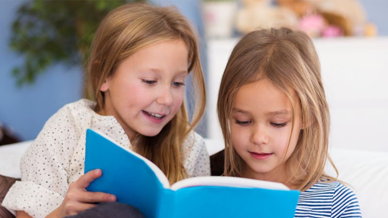 2 girls reading a book