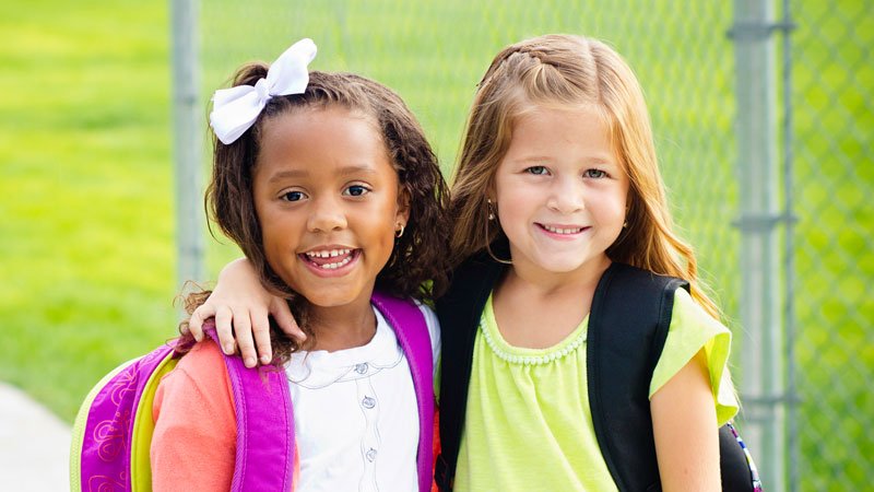 2 young girls smiling with backpacks
